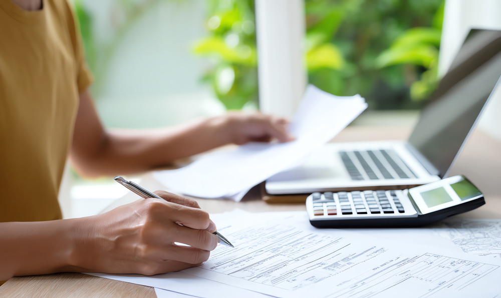 woman managing finances documents home office | EOR-Backed Payroll as a Transitional Model: When and How Startups Should Move Beyond EOR